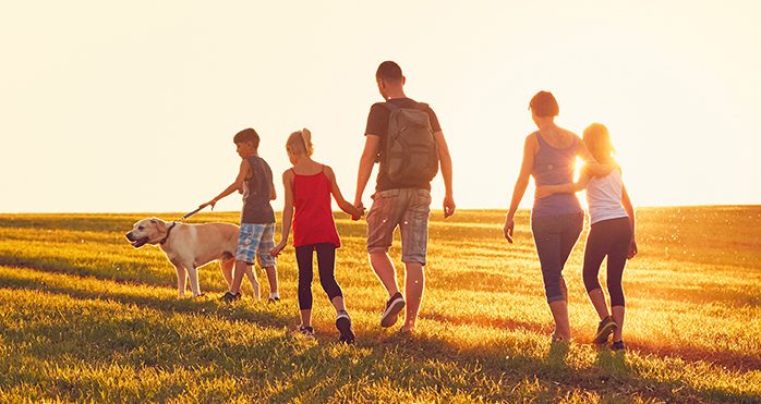 family walking with dog in field